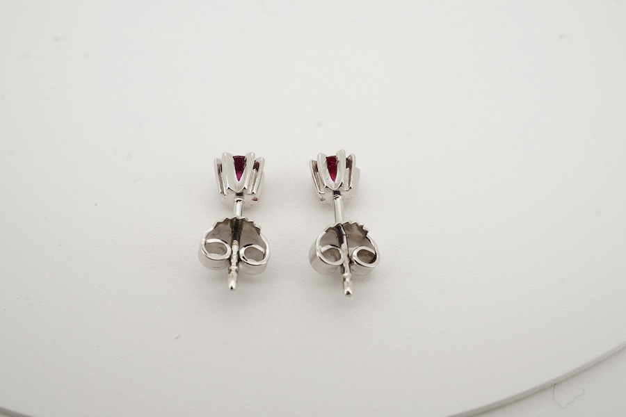 A modern pair of 585 white metal and solitaire ruby set ear studs, overall diameter 5mm, gross weight 1.4 grams. Condition - good